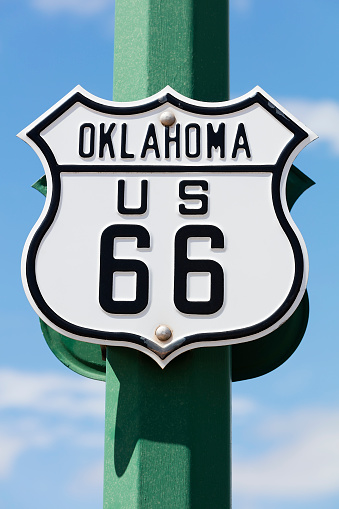 A black and white road sign of the historic Route 66 against blue sky.